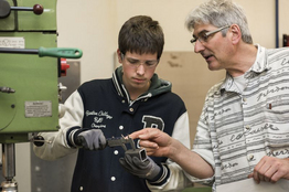 Aufnahme-Metallwerkstatt-Ausbilder zeigt Lernenden wie man ein Loch bohrt