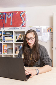 Mädchen sitzt vor Laptop - Stiftung Bühl