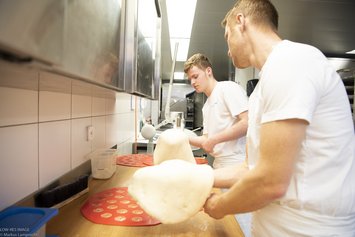Berufsbildungsangebot-Bäckerei-Bäckermeister und Lehrling schwenken Teigg