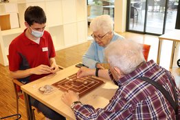 Pfleger spielt mit Senioren Brettspiel - Stiftung Bühl